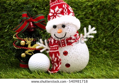 Snowman is smiling with golf ball on green grass background. Idea Christmas present for golfer.