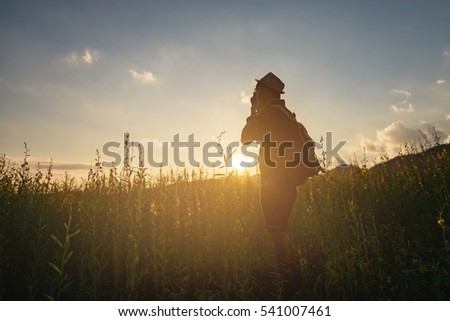 Silhouette of a young who like to travel and photographer, taking pictures of the beautiful moments during the sunset ,sunrise