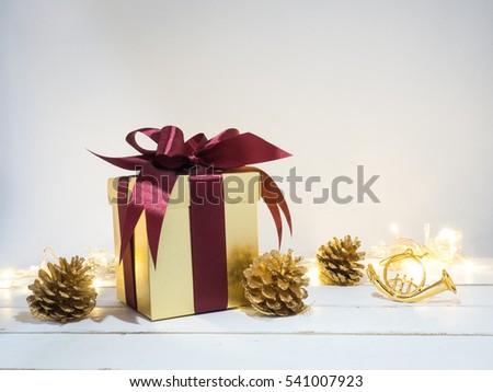 Gold box with red ribbon and decoration golden object white background  on wooden table for Christmas and The New Year .