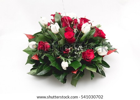 Green funeral fir wreath with red roses isolated on a white background.