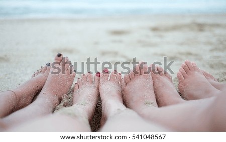 Vacation Time. Foot of four women on sand background