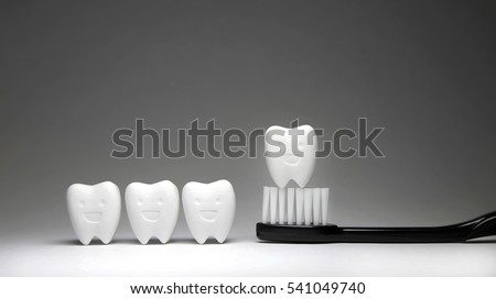 Tooth model in happy emotion and black toothbrush, if brush the teeth, teeth will good healthy