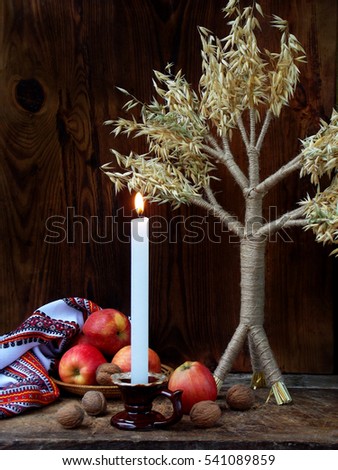 Ukrainian Christmas concept for greeting card. Composition of X?mas symbol didukh, burning candle, apples, walnuts on wooden background. Copy space. Selective focus