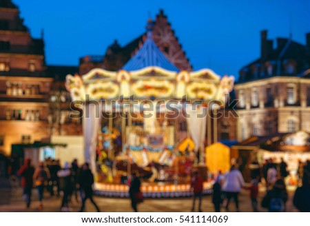 Defocused Christmas Market atmosphere with kids and adults having fun on the merry-go-round carousel in central Strasbourg, France
