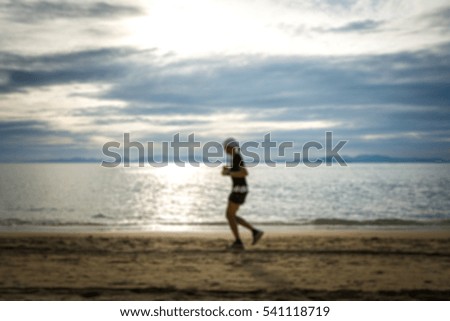 Woman jogging on the beach with sea and sunset background. Blur photo