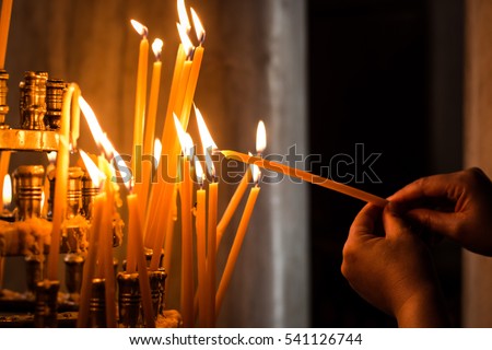 
A woman hand lights a candle inside an orthodox church in the city of Athens in Greece
