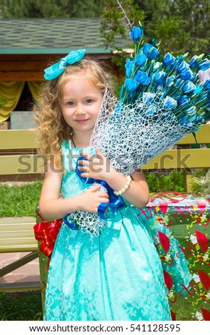 Beautiful happy girl kid with a bouquet of flowers on birthday in park. Celebration concept and childhood, love
