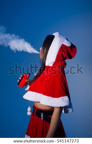 A young Chinese womanvaping electronic cigarette dressed as Santa on a blue background