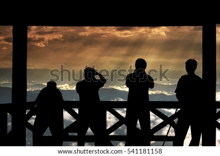 Silhouette of a photographers group who shoots the Fantastic Landscape of Sun ray from the sun over the mountain which have cloud and fog at top view of Doi Samer Dao in nan province, Thailand