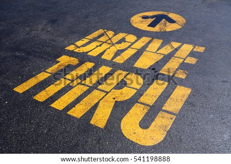 yellow drive thru sign on black asphalt
bright sunlight,  Royalty-Free Stock Photo #541198888