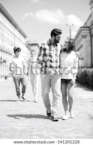 Couple walking on street with friends in background