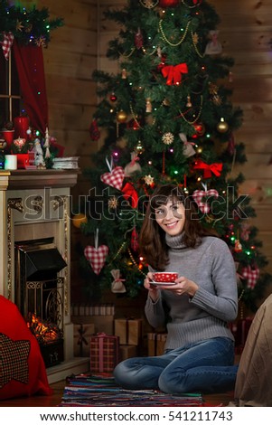  beautiful woman sitting at home by the Christmas tree with a cup.  woman in christmas interior