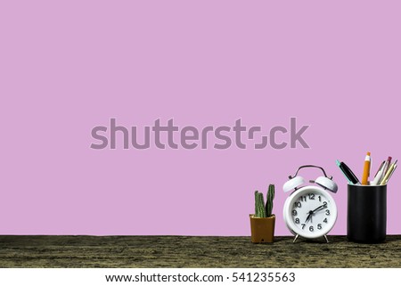 Wooden workplace desktop with table clock, plants on old wooden table. (1)
