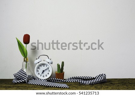 Wooden workplace desktop with table clock, plants on old wooden table.