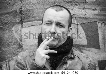 portrait of smoker man in outdoor on graffiti wall background
