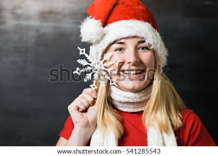 Closeup studio portrait young woman santa claus girl in red hat and white knitted scarf holding snowflakes