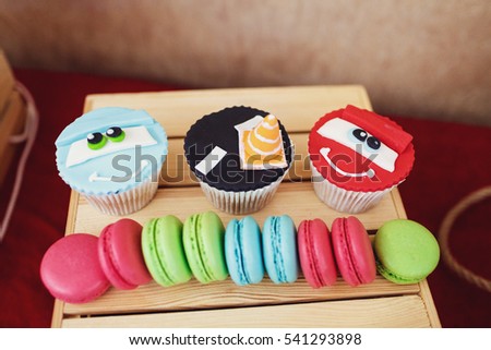 Colorful macaroons and cupcakes served on little wooden box