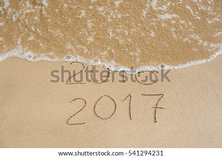 New Year 2017 is coming concept - inscription 2016 and 2017 on a beach sand, the wave is almost covering the digits 2016. Royalty-Free Stock Photo #541294231