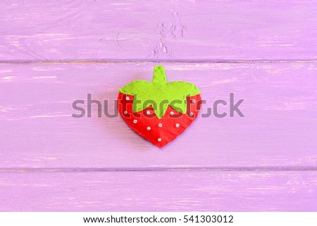 How to hand sew a children toy strawberry. Step. Tutorial. Kids felt toy strawberry isolated on purple wooden background. Easy kids sewing instruction. Top view