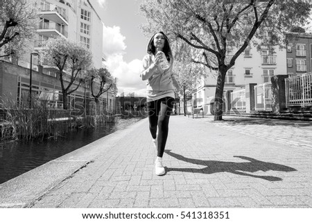 Full length of fit young woman jogging by canal against buildings