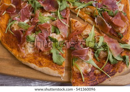 Italian pizza with tomato sauce, cheese, ham and arugula