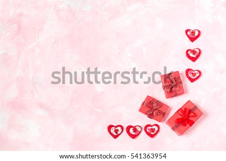 Festive background to Valentines Day. Frame of gift boxes with red ribbon and many different red hearts on a pink textured background. Symbols of love. Flat lay, top view