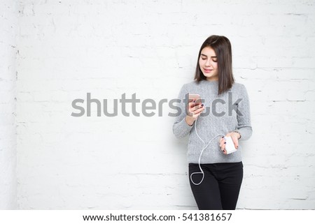 Powerbank in hands. Woman playing in smartphone and charges her phone. Young beautiful girl smiles with a phone and charging in his hand 
