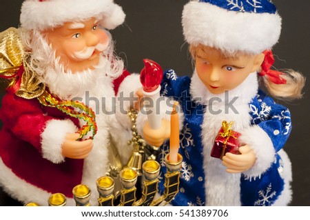 Toy Ded Moroz (Santa Claus) and Snegurochka lighting the Hanukkah candles. In December 2016 Jewish Hanukkah holiday coincides with Christmas and secular New Year.