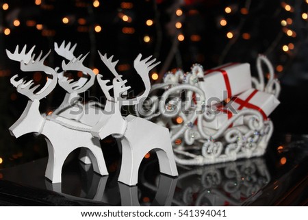 White Christmas sleigh drawn by white reindeer pulling a gifts on a dark background. handmade