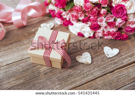 Gift box and bunch of roses on wooden boards. Toned photo.