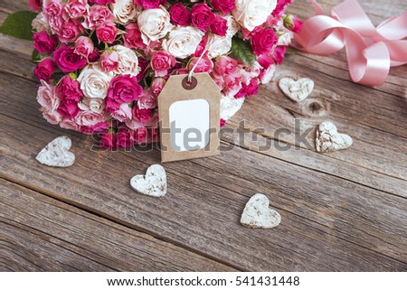 Bouquet of roses and card on wooden boards. Toned photo.