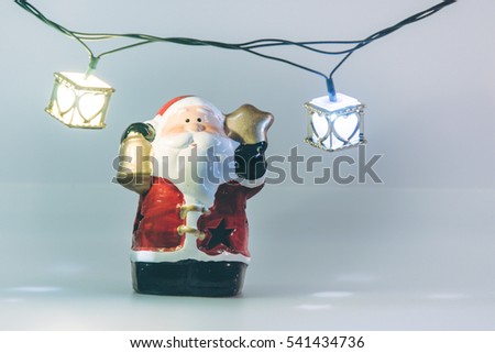 Santa claus and light bulb stand on white background. Snow flake is falling down.