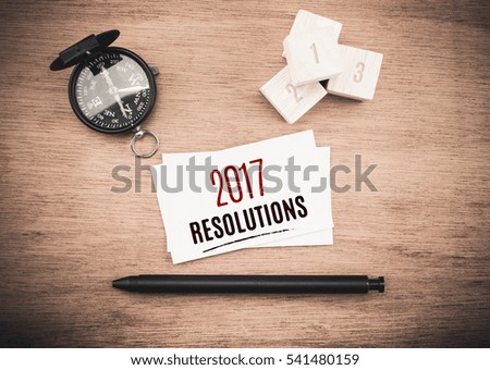 top view of  2017 resolutions word on business card with black pen and compass on wooden table,New year planning