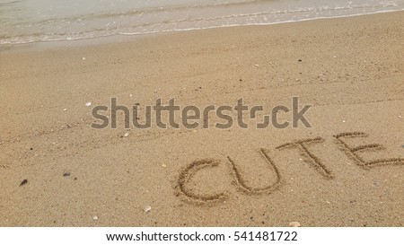 Handwriting words "CUTE" on sand of beach