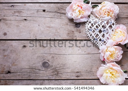 Decorative heart and  pink peonies flowers on aged wooden background. Top view.  Place for text. Selective focus
