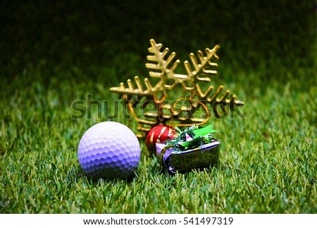 Golf ball with Christmas ornament on green grass. 