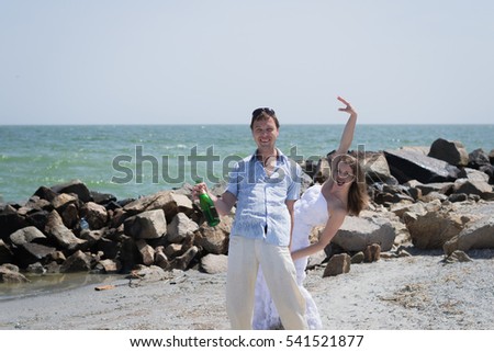 A loving couple walks on the sea. Couple in the summer at sea. Sea Wedding. Bride and groom fooling around. The bride and groom open champagne with splashes.