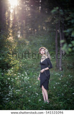 The girl with the owl on his shoulder in the rays of sunset on a forest background