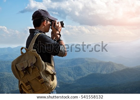 Man Traveler with photo camera and backpack hiking outdoor Travel Lifestyle and Adventure concept.
