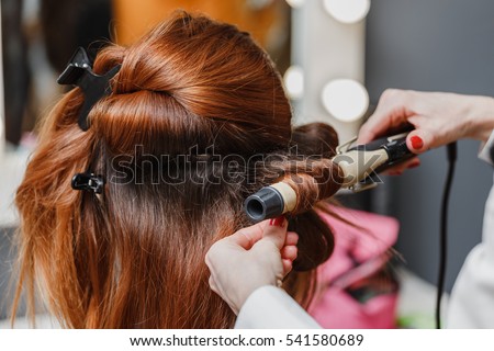 Hairdresser working at the beauty studio salon, making hair style. Royalty-Free Stock Photo #541580689