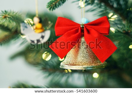 Christmas picture. Bright golden bell with a velvet red bow on a Christmas tree. Background of lights garland                               