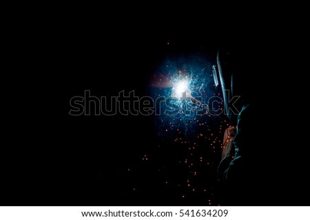 Worker with protective mask welding metal.welding in black background.
