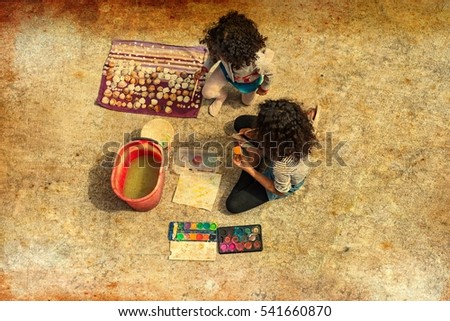 Brazilian girls painting shells on summer day. Top view at two kids sitting on a patio floor painting with watercolors for creative family concept blog, toys business website. Image with filter effect