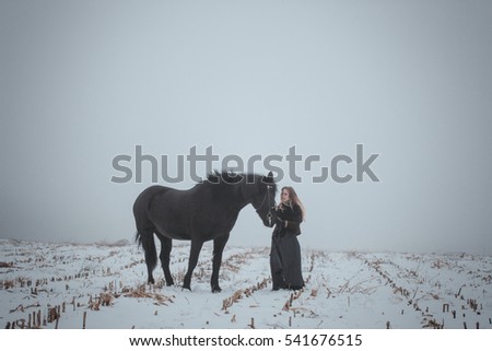 a girl with a horse in a field in winter.