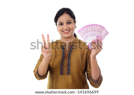 Cheerful woman holding Indian currency notes with victory sign