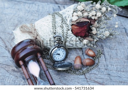 Antique pocket watch and hourglass with dried flowers