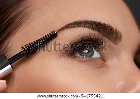 Eyebrows Care. Closeup Of Woman Beautiful Blue Eye, Perfect Shaped Brow, Long Eyelashes With Professional Makeup And Brow Gel Brush. Young Female Model Shaping Brown Eyebrows. High Resolution Image Royalty-Free Stock Photo #541755421