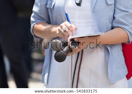 Female journalist taking notes at press conference Royalty-Free Stock Photo #541833175