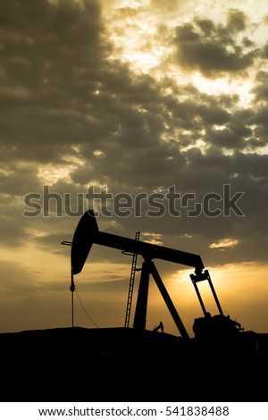 Silhouette of BPU crude oil pump in the oilfield on a cloudy morning sunrise 
