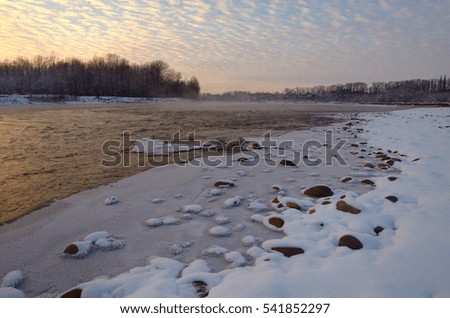 The mountain river in the evening. Stones and snow bank. Caucasus, Russia